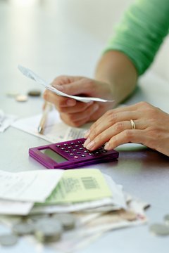 Woman reviewing receipts with calculator, close-up of hands