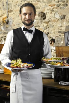 Waiter holding three plates of salad, smiling, portrait