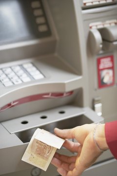 High angle view of a person's hand withdrawing money from an ATM