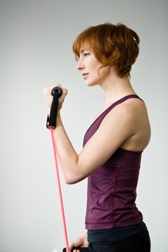 Jupiterimages/Photos.com/Getty Images Biceps curls are performed while standing on one end of the tubing.