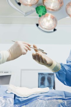 Jupiterimages/Polka Dot/Getty Images Surgical scrub techs hand surgeons instruments and tools during procedures.
