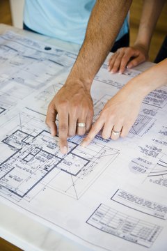Jupiterimages/Creatas/Getty Images Construction managers must know how to read blueprints.