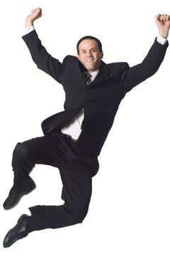a caucasian business man in a dark suit jumps playfully up into the air