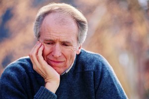 Close-up of man with head on hand with sad look on face