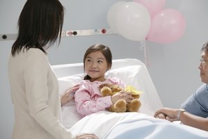 Parents comforting girl holding teddy bear in hospital bed
