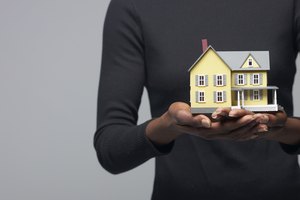 Cropped shot of a woman holding a miniature house