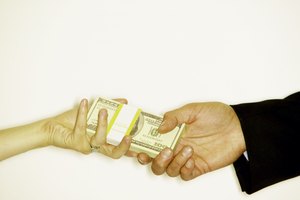 Hands exchanging bundle of hundred dollar bills