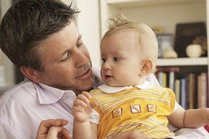 Father holding baby daughter (3-6 months) in living room