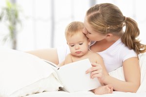 Mother reading  book baby in bed before going to sleep