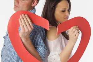 Couple holding two torn parts of a heart