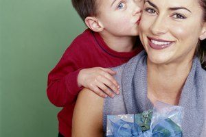 Boy (4-6) kissing mother on cheek, mother holding gift, smiling