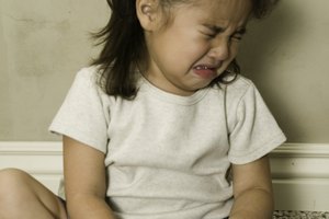 Girl (4-5) sitting on carpet, crying