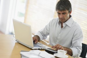 Man using laptop and calculator at desk