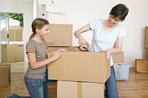 Woman and daughter taping moving boxes