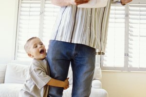 Boy hugging leg of father on phone