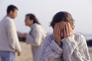 Couple arguing, girl (12-13 years) covering eyes with hands, waist up