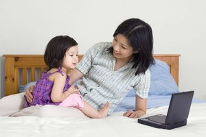 Mother and daughter with DVD player on bed