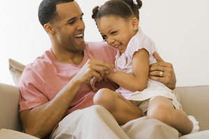 Playful father and daughter on sofa