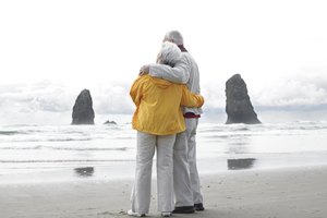 Senior couple embracing on beach, rear view