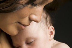 relationship portrait of a young adult mother as she hugs her sleeping newborn baby