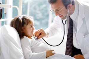 portrait of a male doctor examining a young girl's chest with a stethoscope