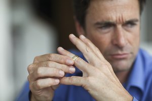 Mature man toying with gold wedding ring on finger