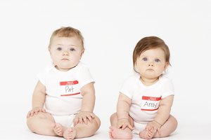 Two babies (6-9 months) sitting on white background
