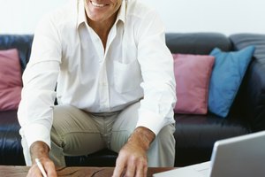 mature man doing paperwork with a laptop in front of him