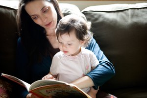 Mother reading to daughter on sofa at home