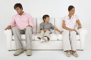 Boy sitting on couch with aloof parents