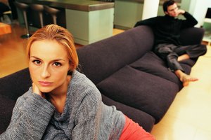 Portrait of a Woman Sitting on a Sofa with a Man in the Background