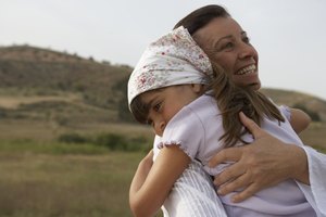 Girl (4-6) and grandmother embracing, smiling, close-up