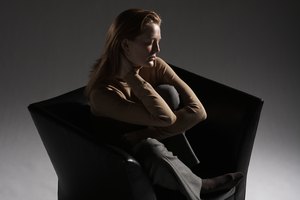 Woman sitting on armchair, hugging knees, elevated view