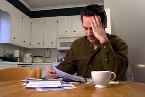 Stressed man paying bills in kitchen