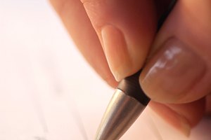 Extreme close-up of woman's hand as she signs her name to a document.