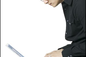 portrait of a young adult man in a black shirt as he sits and works at his computer