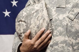 Soldier holding helmet by American flag