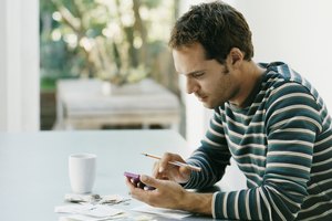 Man Sitting at a Table Using a Calculator