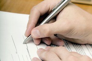 High angle view of a person's hand filling up a form with a pen
