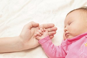 Newborn baby is held by the hand parent