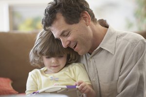 Close-up of girl (4-5) sitting with father and holding slate