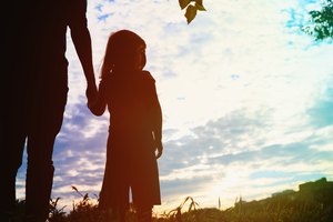 silhouette of father and daughter holding hands at sunset