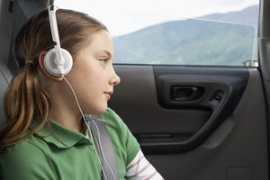 Girl (6-8 years) in car wearing headphones, close-up, side view