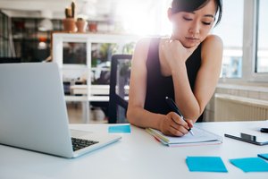 Asian businesswoman writing notes on notepad