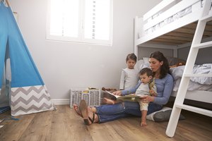 Mother Reading Story To Children In Their Bedroom