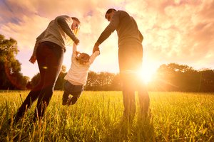 Parents hold baby's hands.  Happy family in park evening