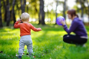 Toddler with his mother playing ball