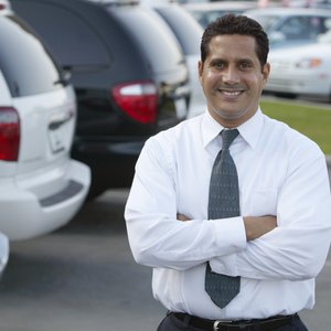A car salesman stands in his dealership lot