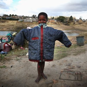 A young orphan holding up a donated coat.