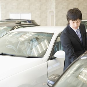 A car salesman inspecting one of his cars